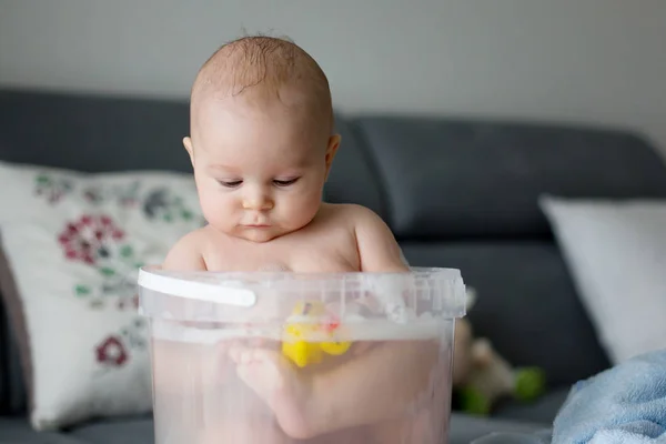 Cute little four month old baby boy, playing in bucket full with