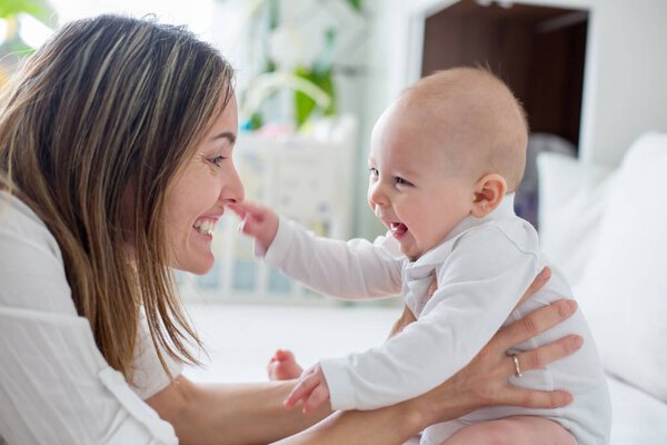 Молодая мать лежала в постели со своим новорожденным мальчиком, играя в тог
