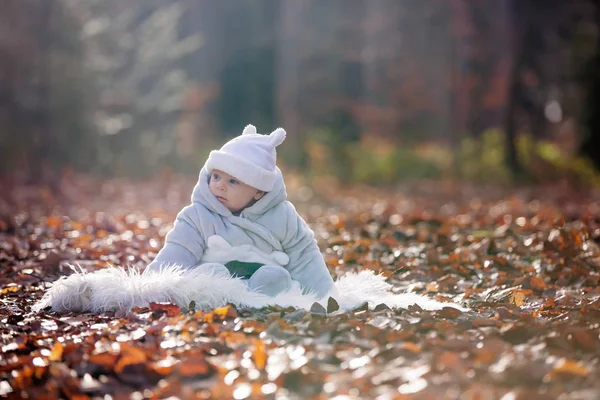 Bambino, seduto su una pelliccia bianca nella foresta — Foto Stock