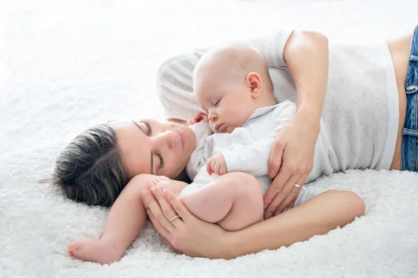 Madre y su hijo bebé, durmiendo en una cama grande, luz de fondo suave — Foto de Stock