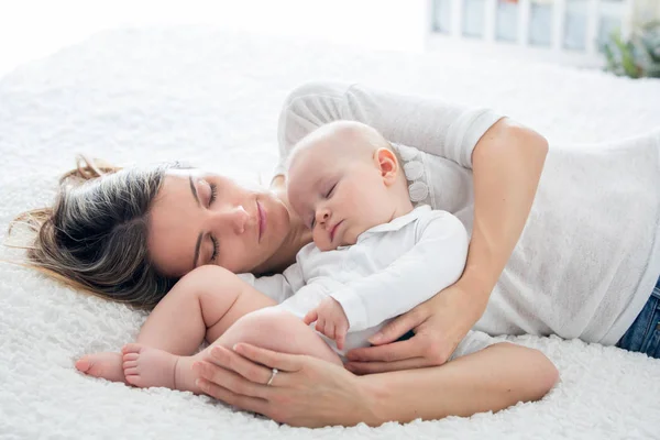 Madre y su hijo bebé, durmiendo en una cama grande, luz de fondo suave — Foto de Stock
