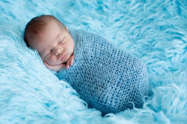 Şirin bebek çocuk, huzur içinde uyuyor gebertecek şal bir blu üzerinde sarılı