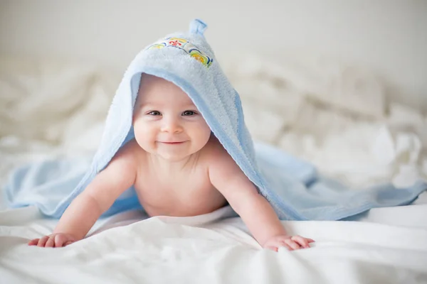 Söt liten pojke, slappar i sängen efter bad, leende happil — Stockfoto