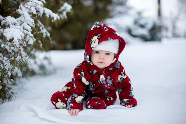 Kleine schattige lachende baby jongen, zitten buiten in de sneeuw — Stockfoto