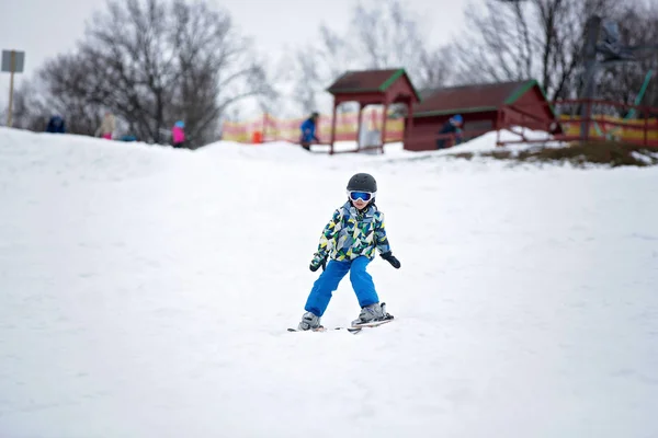 Mignon petit enfant d'âge préscolaire en veste bleue, skier heureux sur un — Photo