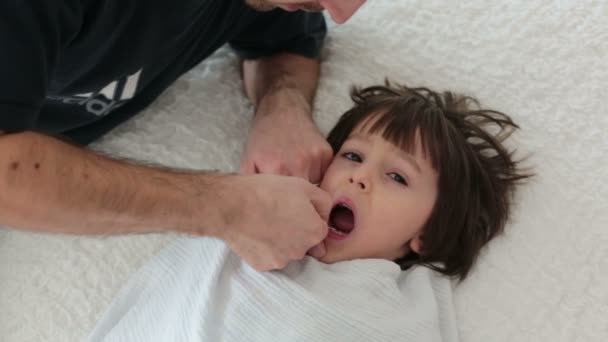 Ojciec Próbuje Wyciągnąć Swojego Syna Zęba Dziecko Siedzieć Łóżku Tata — Wideo stockowe