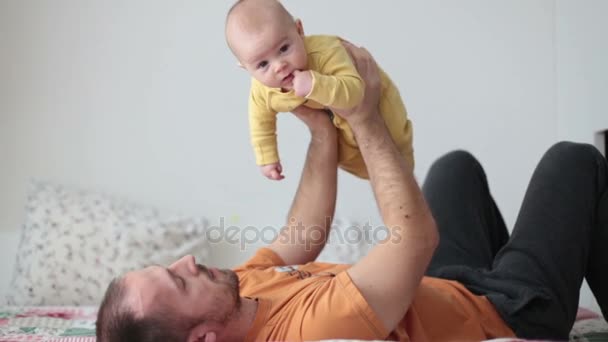 自宅で赤ちゃんが楽しそうに笑っている 空気中の飛行機のような彼を保持している彼の息子と遊ぶ — ストック動画