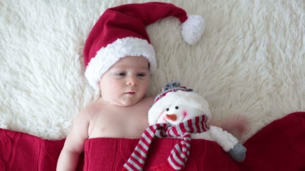Karácsonyi portré-aranyos kis újszülött fiú, viselt santa kalap és átölelve kis játék aranyos hóember, Műterem lövés, téli idő