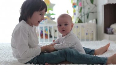 Küçük çocuk, yatak odasında küçük kardeşiyle oynuyor.