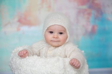 Küçük şirin bebek çocuk, el yapımı örgü beyaz teddy giyinmiş olmak