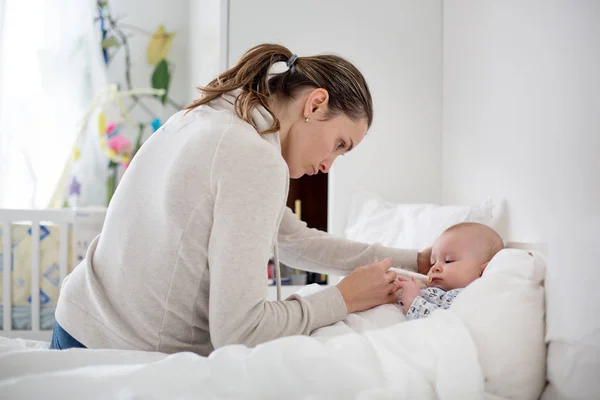 Cute sick child, baby boy, staying in bed, mom giving him medici — Stock Photo, Image