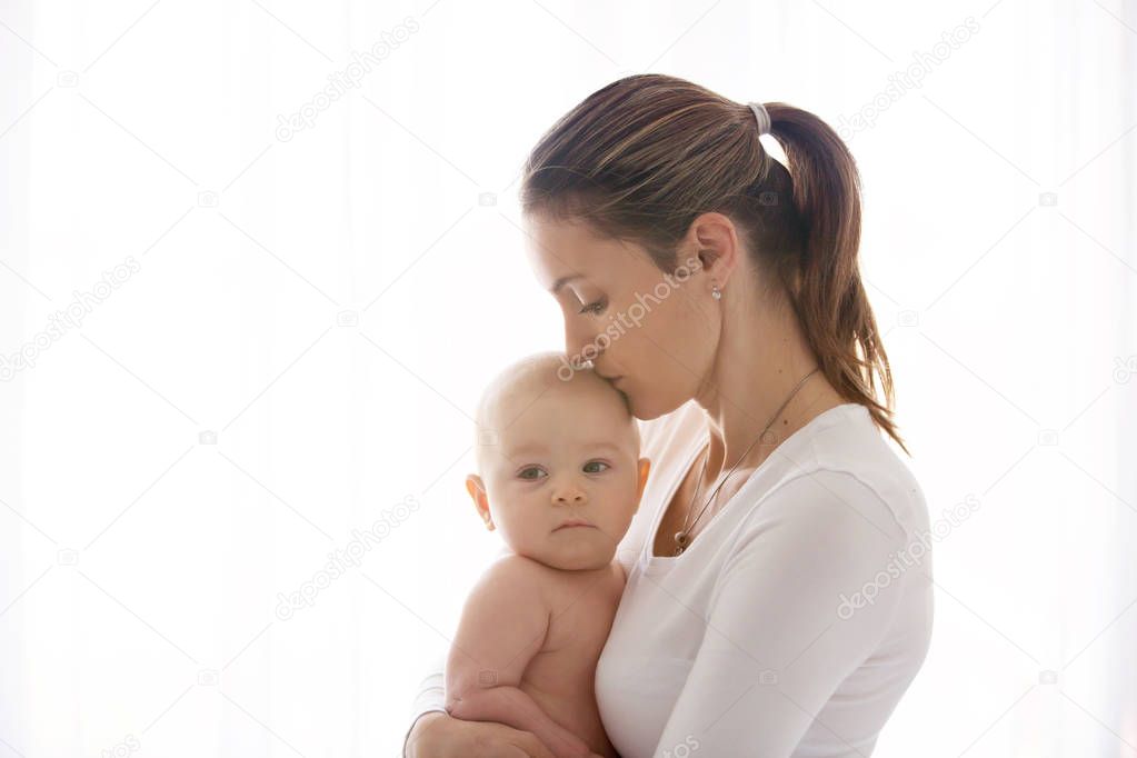 Mother, holding her sick baby boy, sad baby, isolated on white 