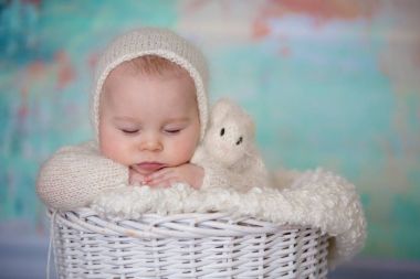 Küçük şirin bebek çocuk, el yapımı örgü beyaz teddy giyinmiş olmak