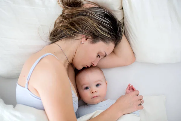 Joven madre amamanta a su bebé, sosteniéndolo en sus brazos y s — Foto de Stock