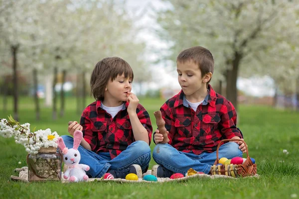 Two children, boy brothers, eating chocolate bunnies and having — Stock Photo, Image