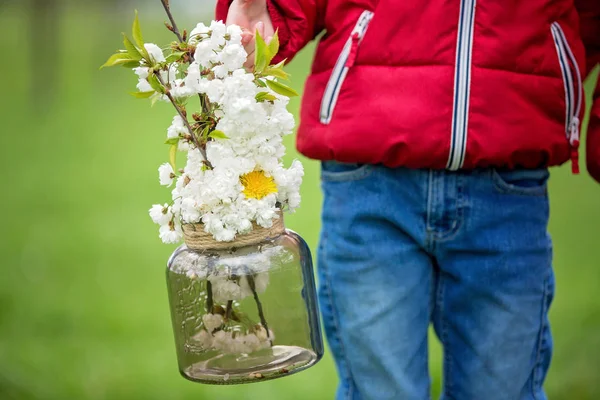Aranyos gyermek, gazdaság jar, tavaszi virágokkal, a parkban — Stock Fotó