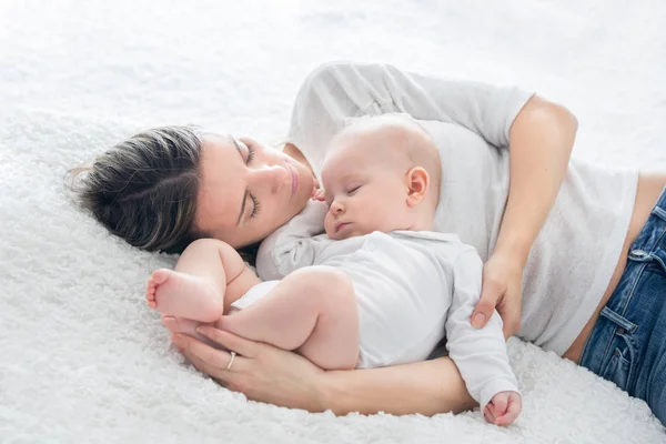 Madre y su hijo bebé, durmiendo en una cama grande, luz de fondo suave —  Fotos de Stock