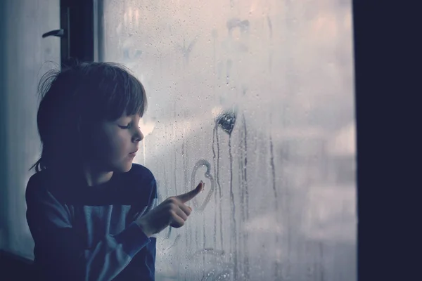 Kisfiú, így ujjlenyomatok és rajz szív, egy ablak — Stock Fotó