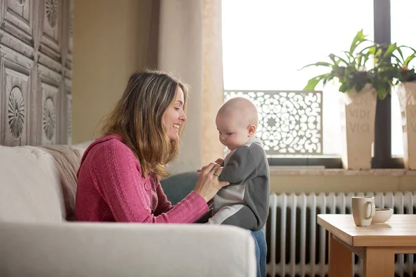 Młoda matka, trzymając jej toddler chłopiec, karmienie piersią, go w domu — Zdjęcie stockowe