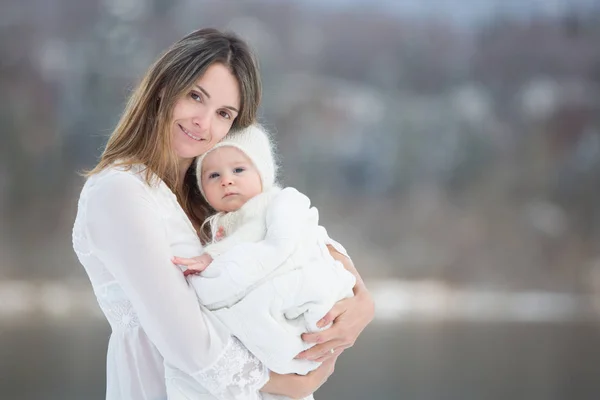 Beautiful mother in white dress and cute baby boy in knitted one — Stock Photo, Image
