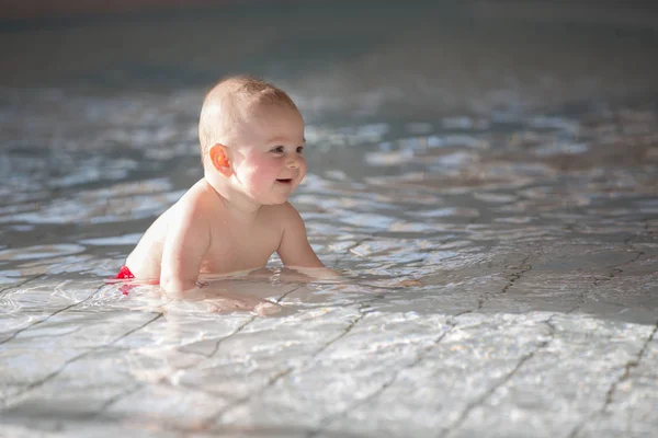 Pequeno menino bonito, nadando feliz em uma água de piscina rasa — Fotografia de Stock