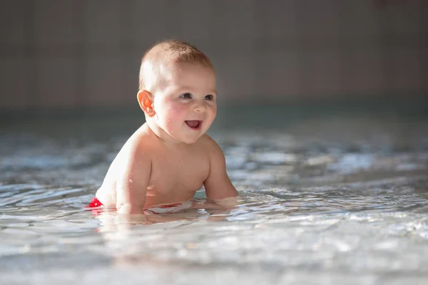Piccolo bambino carino, che nuota felicemente in una piscina poco profonda — Foto Stock