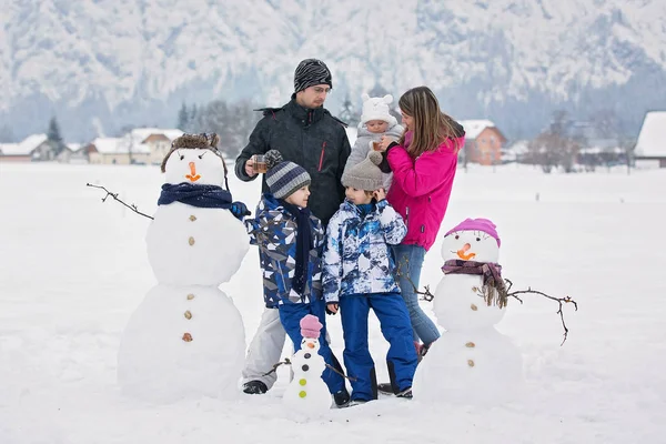 Família com crianças, construindo boneco de neve no parque em pouco mal — Fotografia de Stock