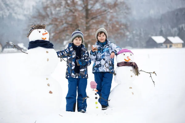 Famiglia con bambini, costruzione pupazzo di neve nel parco in poco male — Foto Stock