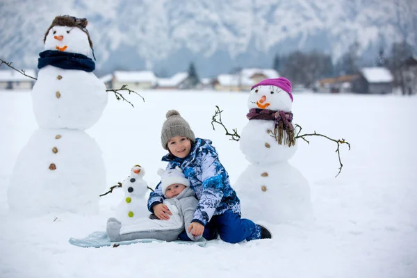 Gezin met kinderen, gebouw sneeuwpop in het park in kleine vil — Stockfoto