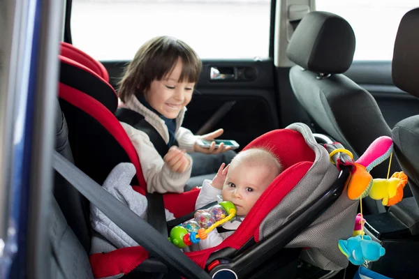 Kleiner Junge und sein älterer Bruder, die in Autositzen reisen, g — Stockfoto