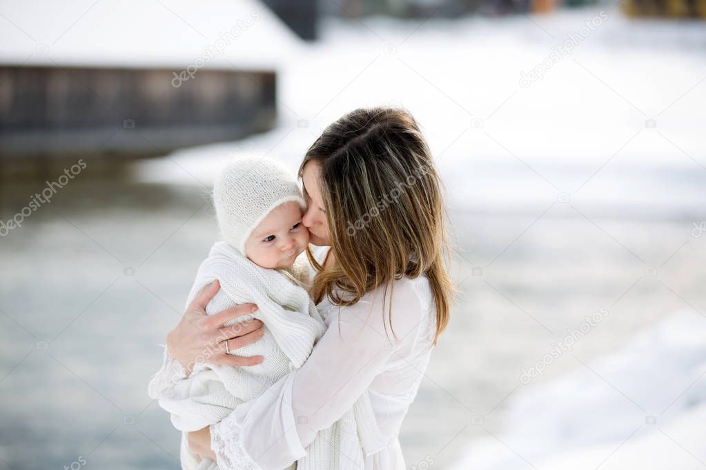Beautiful mother in white dress and cute baby boy in knitted one