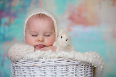 Küçük şirin bebek çocuk, el yapımı örgü beyaz teddy giyinmiş olmak