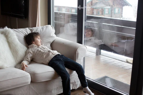 Niño preescolar, sentado junto a la ventana en la sala de estar, mirando — Foto de Stock