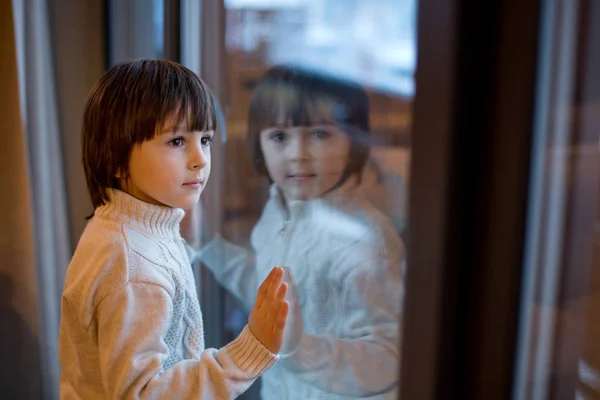 Preschool jongen, zitten bij het raam in de woonkamer, kijken naar — Stockfoto