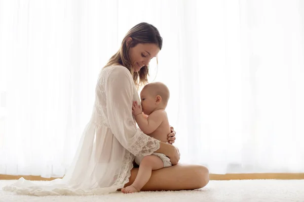 Fiatal anya szoptatja újszülött kisfiát otthon — Stock Fotó