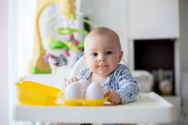 Mignon petit garçon tout-petit, jouer avec des œufs en plastique, assis dans un — Photo