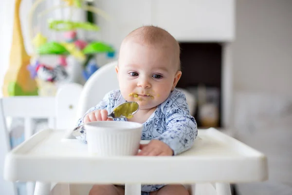 Schattige kleine baby jongen, gepureerde groenten eten voor de lunch, moeder fe — Stockfoto
