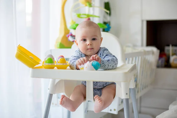 Χαριτωμένο μικρό αγόρι toddler, παίζοντας με πλαστικά αυγά, κάθεται σε ένα — Φωτογραφία Αρχείου