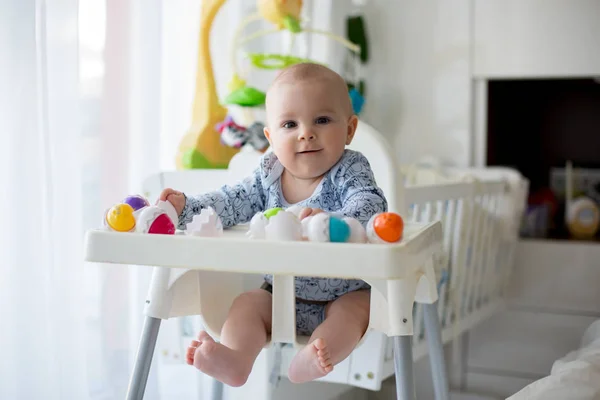 Bonito menino criança, brincando com ovos de plástico, sentado em um — Fotografia de Stock