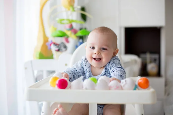 Schattige kleine peuter jongen, spelen met kunststof eieren, zittend in een — Stockfoto