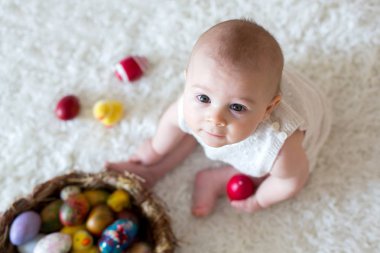 Renkli Paskalya yumurtaları ile oynayan sevimli küçük yürümeye başlayan çocuk oğlu, 