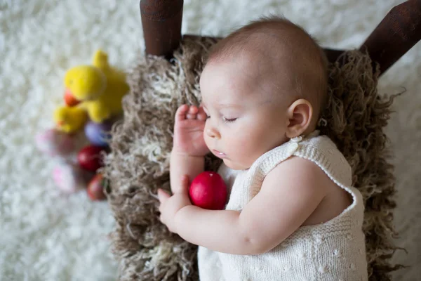 Lindo niño pequeño bebé, durmiendo con huevos de Pascua coloridos — Foto de Stock