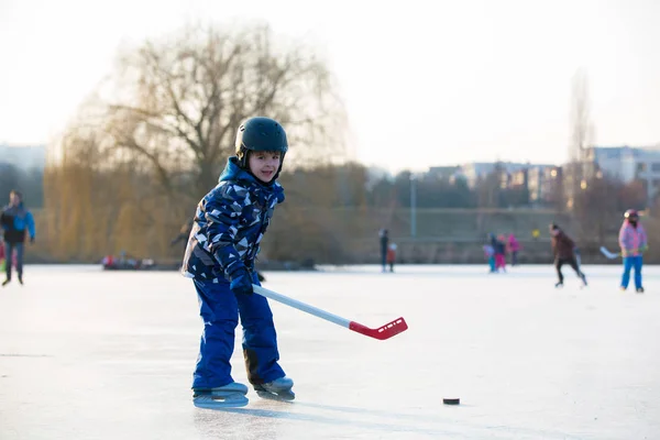 Τα παιδιά, παίζοντας χόκεϊ και πατινάζ στο πάρκο σε παγωμένη λίμνη, — Φωτογραφία Αρχείου