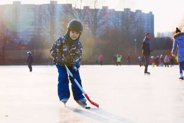 Τα παιδιά, παίζοντας χόκεϊ και πατινάζ στο πάρκο σε παγωμένη λίμνη, — Φωτογραφία Αρχείου