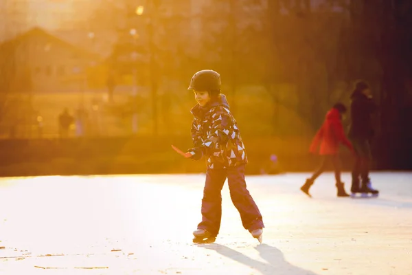 Kinder spielen Hockey und Schlittschuhlaufen im Park am zugefrorenen See, — Stockfoto