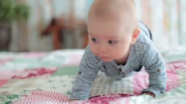 Mutlu bir şekilde gülümseyerek, yatakta yatan, oynayan erkek bebek,