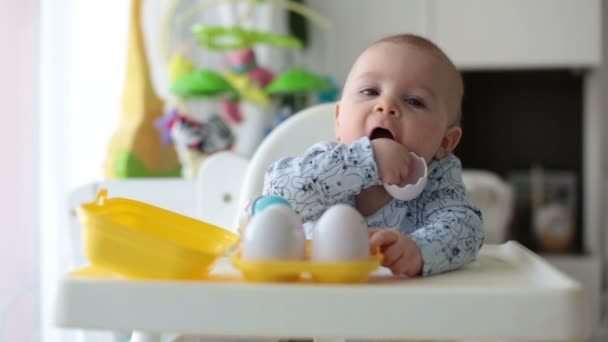 Menino Bonito Brincando Com Ovos Plástico Sentado Uma Cadeira Branca — Vídeo de Stock