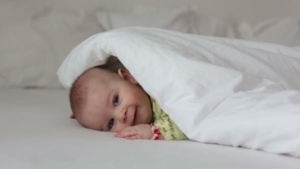 かわいい ヶ月歳の赤ちゃん男の子 自宅の寝室のベッドの布団の下で遊んで幸せそうに笑って — ストック動画