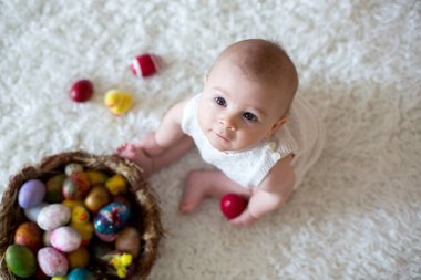 Renkli Paskalya yumurtaları ile oynayan sevimli küçük yürümeye başlayan çocuk oğlu, 