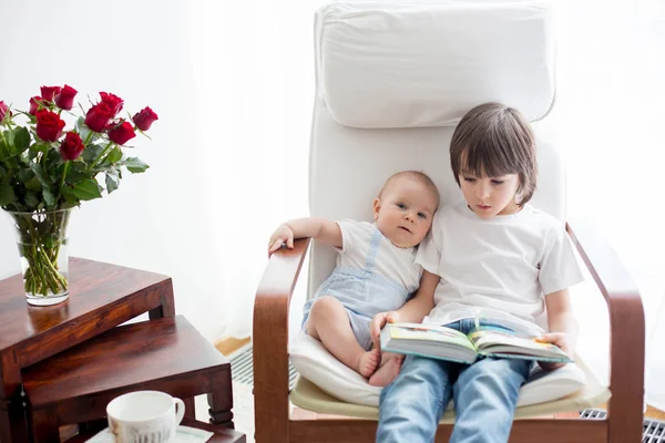 Маленький дошкольник, читает книгу своему младшему брату — стоковое фото